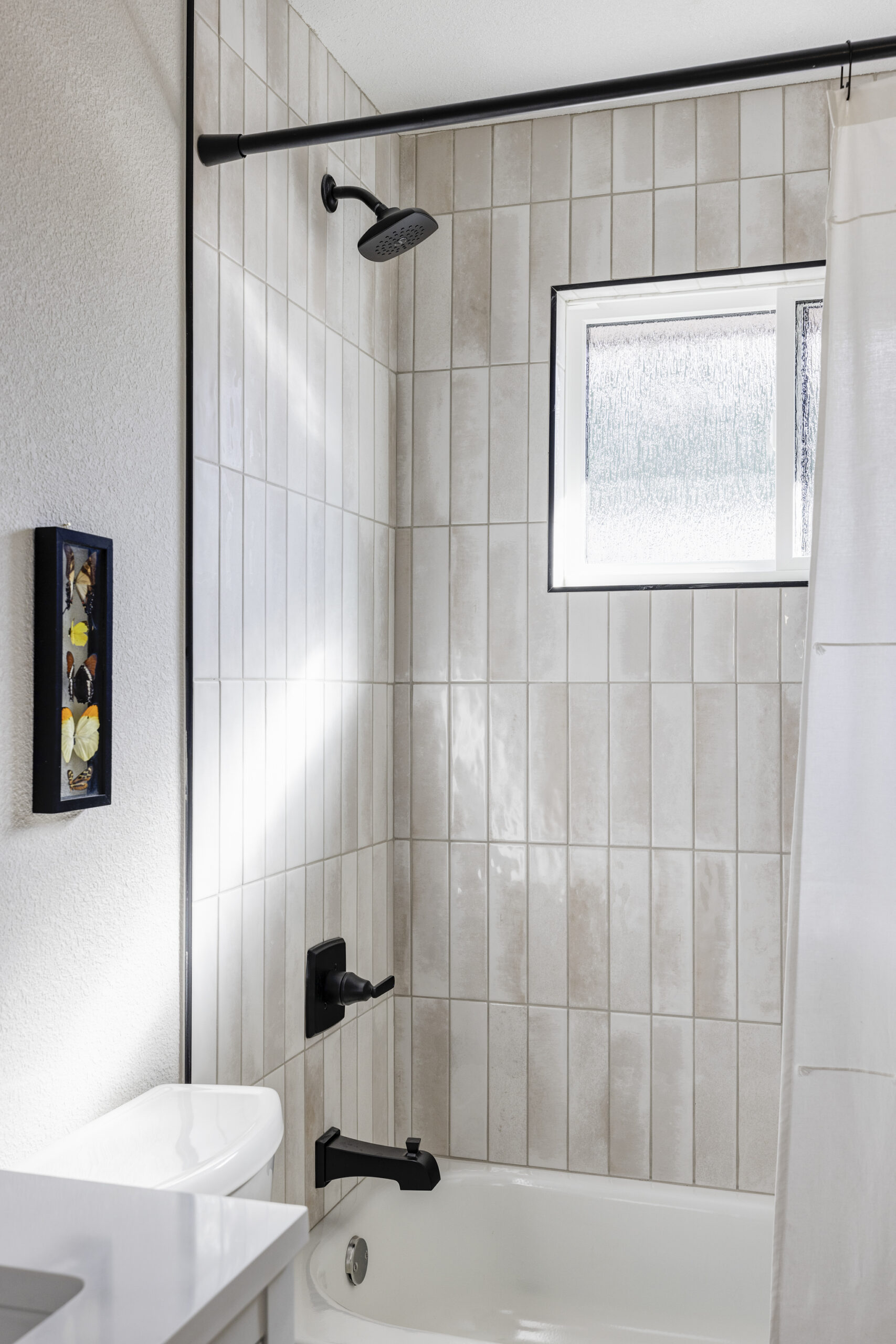 guest bathroom with window in show and vertical tile in shower